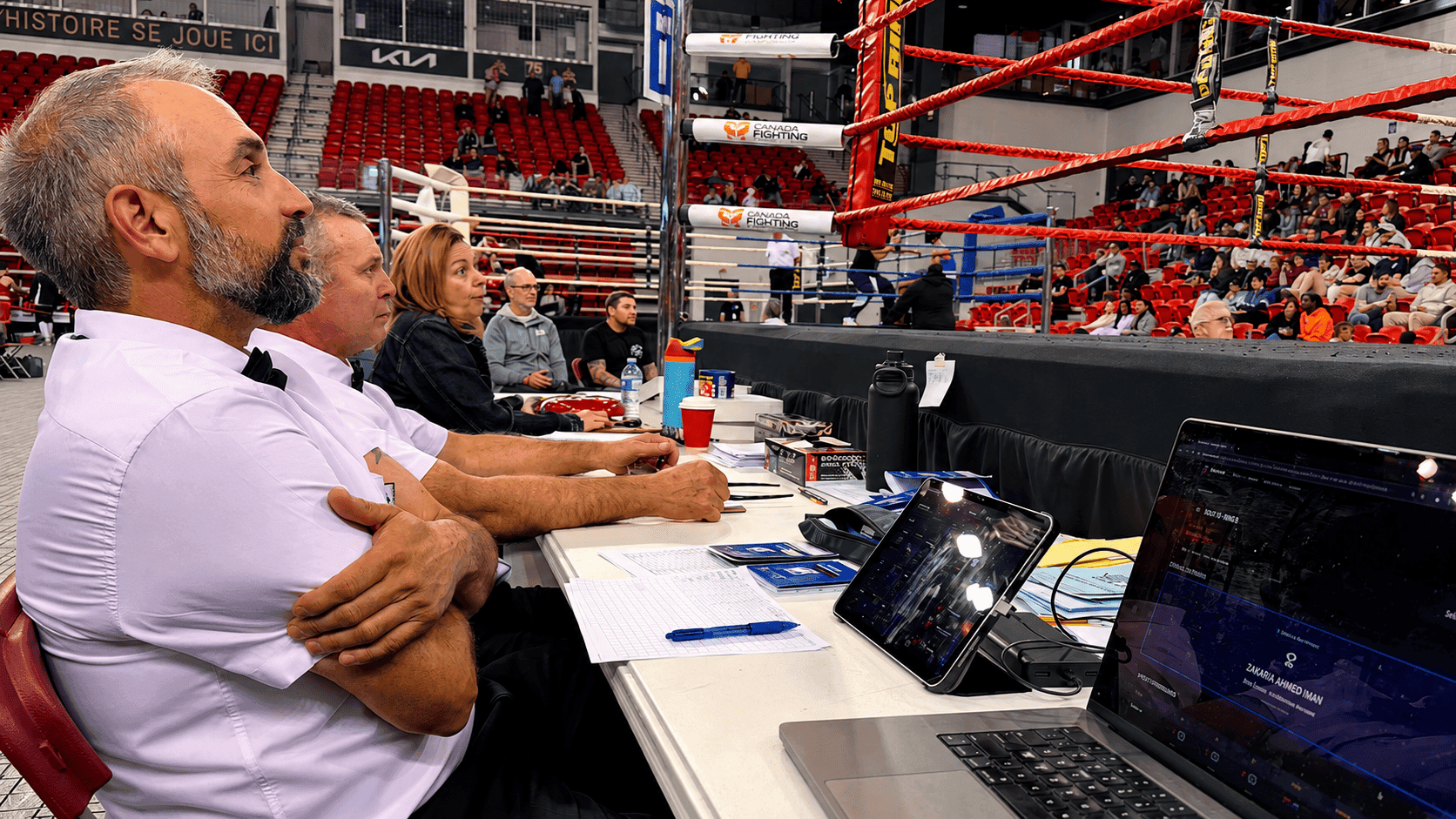 Ringside boxing officials using RingScore beside the ring during a live event.