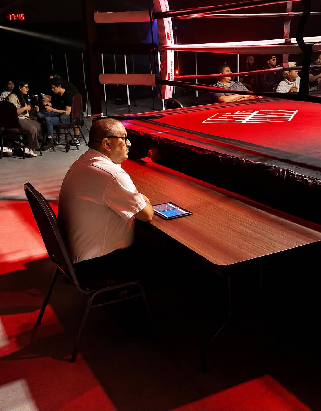 A boxing judge seated ringside with a RingScore scoring device.
